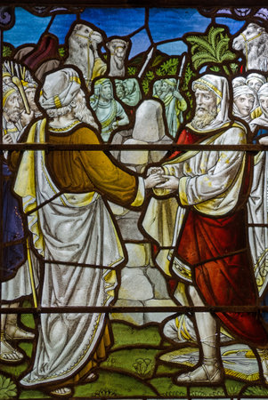 A Victorian stained glass window showing two men making an emotional agreement or Mizpah as described in the Old Testament parable of Jacob and Laban. Historic window on public display over 100 years.のeditorial素材
