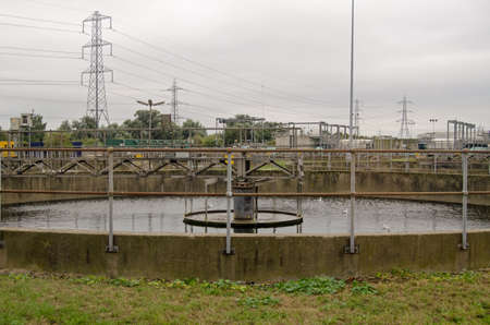 View of a primary settlement tank at a sewage treatment works on an overcast afternoon in Autumn.  Sewage is left in the circular tank and solids fall to the bottom to be scraped up and pumped away.の写真素材