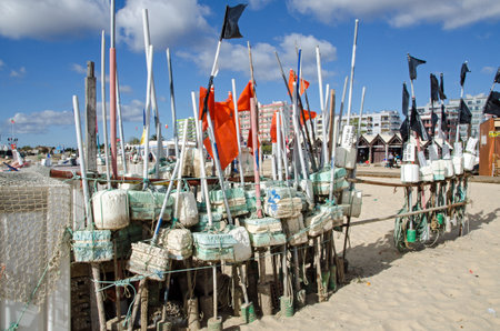 Monte Gordo, Portugal - November 18, 2019: Floats and nets belonging to local fishermen, drying in the sunshine on the sandy beach of  the seaside resort of Monte Gordo on Portugal's Algarve Coast.のeditorial素材