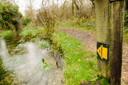 Marker arrow showing the route of the Itchen Way alongside the River Itchen in the Hampshire village of Itchen Stoke on a cloudy autumn day.の写真素材