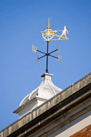 An historic weather vane showing a fusilier wearing the uniform of the King's Royal Hussars firing a cannon. Roof of the Peninsula Barracks, Winchester, Hampshire.の写真素材