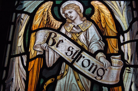 An angel holding the banner reading Be Strong. Fragment of a memorial stained glass window created in 1911 to commemorate a soldier killed during World War One. On public display at St Mary's Church, Tyneham, Dorset.のeditorial素材