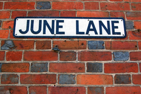 Road sign for the street June Lane fixed to a brick wall.の写真素材