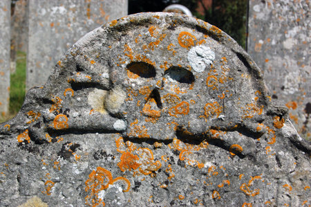 The top of an 18th century tombstone with a skull and crossbones carved into it.のeditorial素材