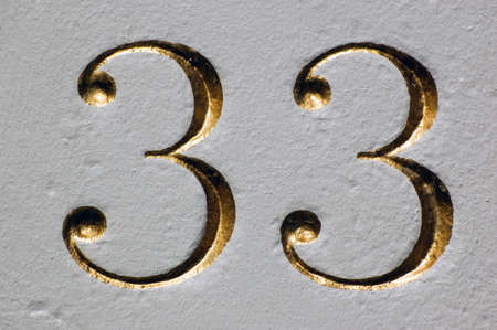 A carved and gilded number thirty three on the outside of an historic building in central London.