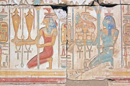 An Ancient Egyptian hieroglyphic carving showing two priestesses carrying wine and food offerings for the gods. Temple of Ramses, Abydos, Egypt.の写真素材