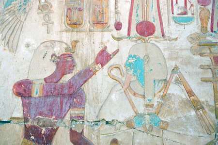 Ancient egyptian painted hieroglyphic carving of the Pharoah Seti with the god of regeneration...