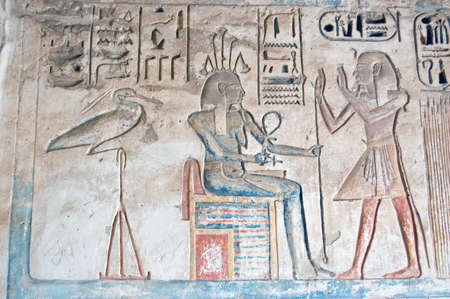 An Ancient Egyptian hieroglyphic carving showing the Pharoah Ramses II praising the goddess of the Nile - happy - and an Ibis water bird. Carving thousands of years old on a wall at the Temple of Medinet Habu on the West Bank of the Nile at Luxor, Egypt.の写真素材