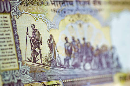 An Indian banknote showing the country leader Mahatma Gandhi leading a line of his fellow countrymen and women on a journey.  Partial view of used banknote, shallow depth of fieldの写真素材