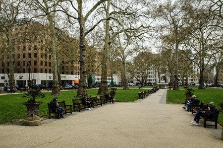 London, UK - April 21, 2021: People enjoying the public benches in the famous Berkeley Square in Mayfair, London on a chilly spring afternoon.のeditorial素材