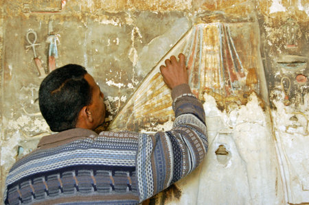 Luxor, Egypt - January 4, 2006: A restorer working on a painted bas relief sculpture in the Ancient Egyptian temple of Medinet Habu on the West Bank of the River Nile in Luxor, Egypt.のeditorial素材