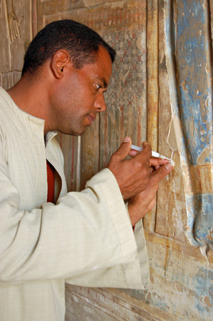 Luxor, Egypt - January 4, 2006: A restorer repairing cracked and flaking stone on a painted bas relief carving on a wall of the historic Medinet Habu Temple on the West Bank of the Nile at Luxor, Egypt.のeditorial素材