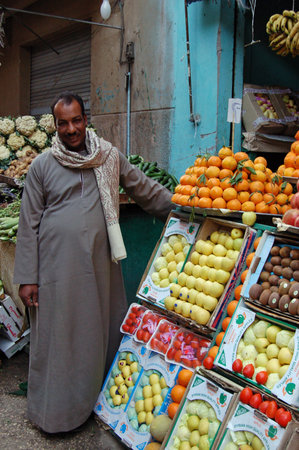 Luxor, Egypt - January 8, 2006:  A smiling greengrocer by the display of fresh fruit and vegetables outside his shop in central Luxor.のeditorial素材