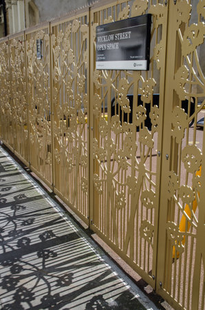 London, UK - April 16, 2021: A pretty floral inspired cast iron fence protecting the play area in Wicklow Street in the King's Cross district of Camden, London.  The fence makes a pretty shadow on the pavement.のeditorial素材