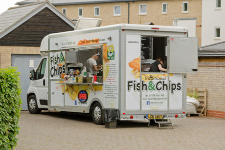 Basingstoke, UK - June 16, 2021: Staff in DB's Fish and Chips van providing hot food at the Community Centre in Sherfield Park, Basingstoke on a summer evening.のeditorial素材