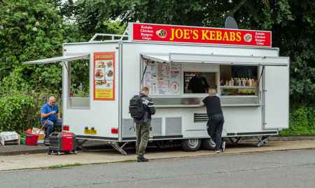Basingstoke, UK - July 3, 2021: Customers waiting for their food at Joe's Kebabs van parked in a lay by in Basingstoke, Hampshire on a summer evening.のeditorial素材