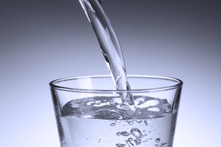pour clear water into the glassの写真素材