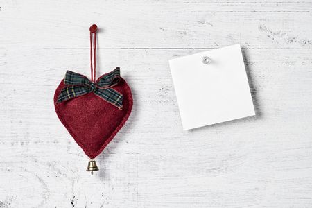 red heart-shaped Christmas decoration hanging on a wooden boardの写真素材