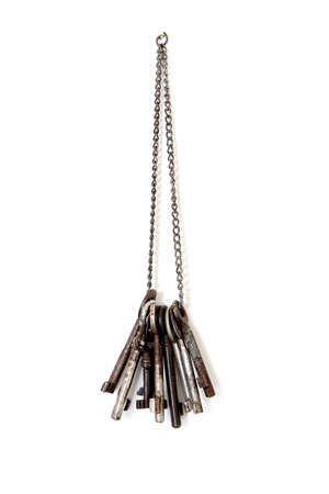 a bunch of various old keys hanging on a chain isolated on a total white backgroundの写真素材