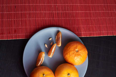 Tangerines with slices in plate on black and red backgroundの写真素材