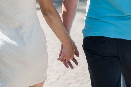 Young couple in love walking in the autumn park holding hands looking