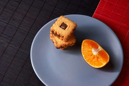 chocolate chip cookies and orange on gray plate and on red with black tableの写真素材