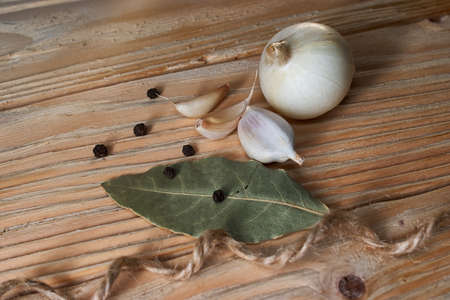 onion, garlic, black pepper and bay leaf on a wooden tableの写真素材