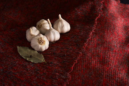 garlic, black pepper and bay leaf on dark red textileの写真素材