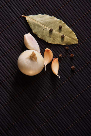 Garlic, onion, bay leaf, black pepper on black table. Garlics. sliced garlic, garlic clove garlic bulbの写真素材