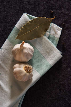 On the green napkin, seasonings: garlic, black pepper peas and bay leafの写真素材
