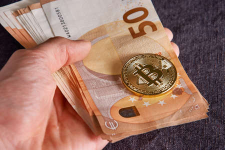hand with bitcoin and 50 fifty euros of backgrounds bills banknotesの写真素材