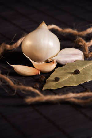 onion, garlic, black pepper and bay leaf on a black tableの写真素材