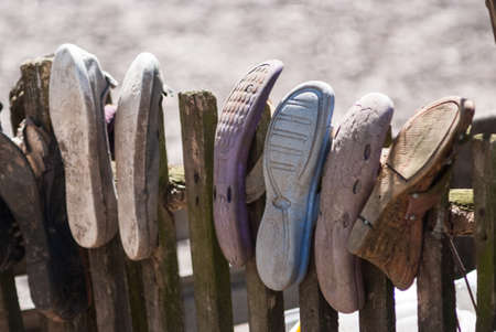 Old worn house slippers on wooden fence. Symbol of poor. the concept of povertyの写真素材