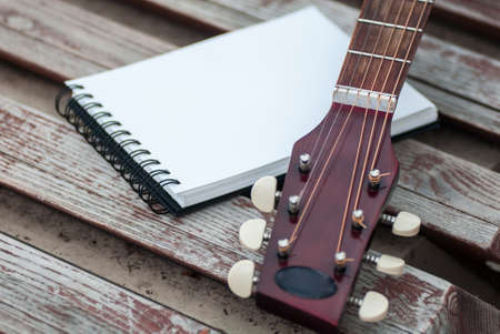 Acoustic guitar and notepad with mock up on the banch