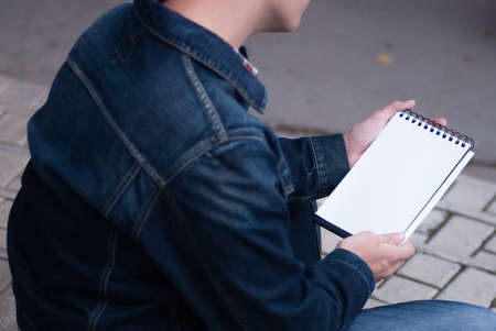Male hand holding a book and sitting outside mock upの写真素材