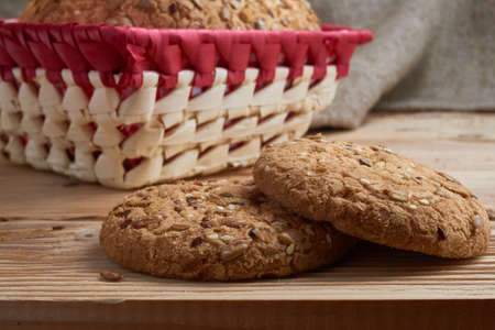 homemade oat cookies with sunflower seeds in and near basket on wooden tableの写真素材
