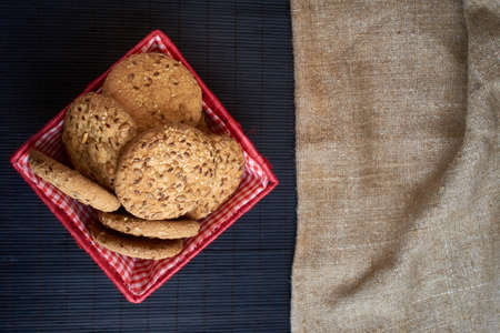 Savory cookies sprinkled with sesame seeds, sunflower on a wooden table and burlap backgroundの写真素材