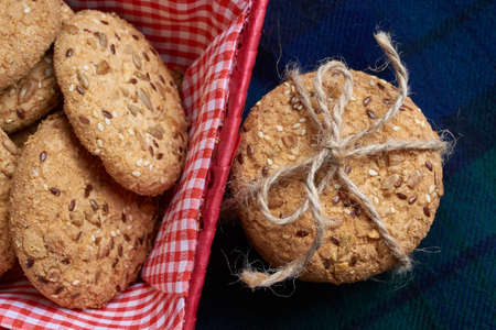homemade oat cookies with sunflower seeds in and near red checkered basket on blue backgroundの写真素材