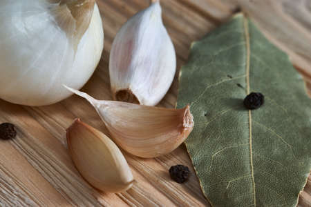 onion, garlic, black pepper and bay leaf on a wooden tableの写真素材