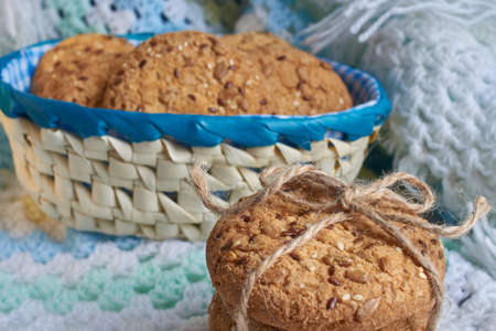 homemade oat cookies with sunflower seeds in and near bluecheckered basket on white and blue backgroundの写真素材