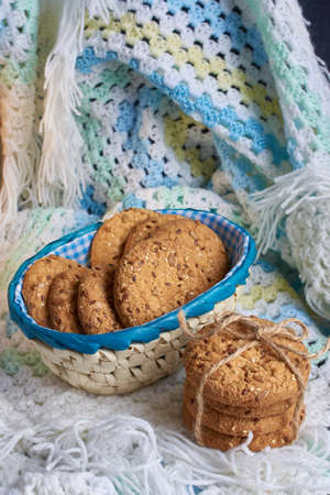 homemade oat cookies with sunflower seeds in and near bluecheckered basket on white and blue backgroundの写真素材