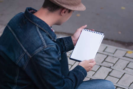 Male hand holding a book and sitting outside mock upの写真素材