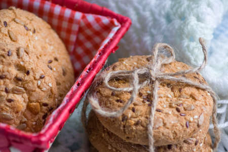 homemade oat cookies with sunflower seeds in and near red checkered basket on white and blue...