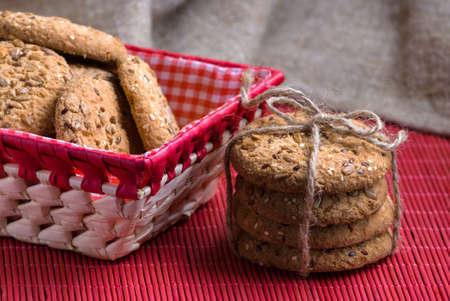 homemade oat cookies with sunflower seeds in and near red checkered basket on wooden tableの写真素材