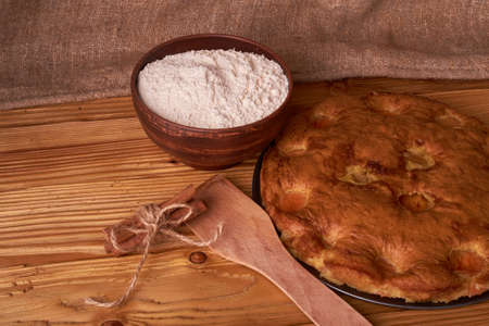 apricot pie and a bowl with flour and other ingredients on wooden table