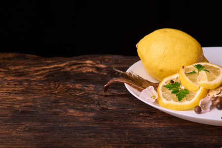 On a wooden table plate with roasted carp fish dorado with parsley, chives and lemonの写真素材