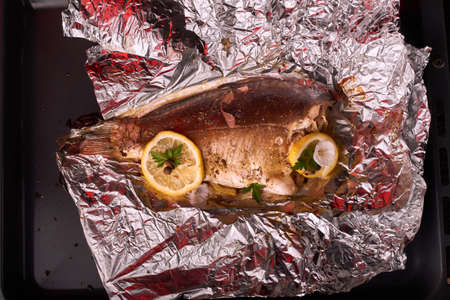 Grilled fish with herbs and lemon on wooden background, top view. Mediterranean luxurious seafood conceptの写真素材