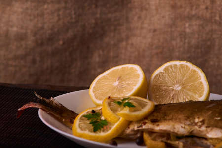Grilled fish with herbs and lemon on wooden background, top view. Mediterranean luxurious seafood conceptの写真素材