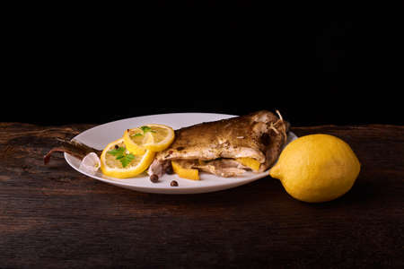 Appetizing baked fish, covered with juicy lemons, garlic and salt on sideの写真素材