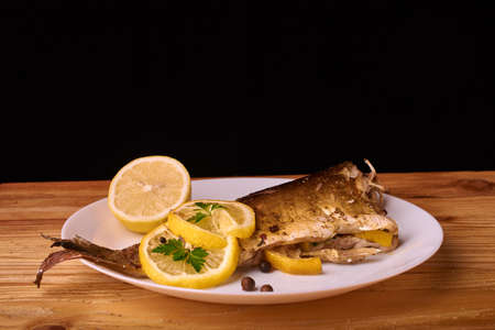 delicious roasted carp fish with lemon slices, spices, and fresh rosemary on baking sheet, view from...